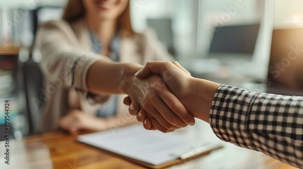 Fototapeta a woman shakes hands with an employer at a desk, ready to give an offer. generative AI