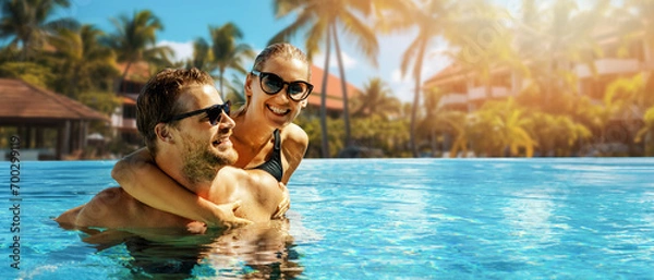 Fototapeta smiling happy couple having fun together in resort swimming pool. summer vacation, getaway travel. banner with copy space