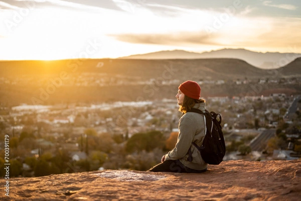 Fototapeta Portrait Person With Bright Red Beanie in St George, Utah Dixie Rock wearing Backpack Outside Sunset Golden Hour Red Rocks