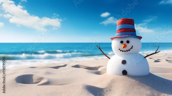 Obraz A snowman is standing in the sand on the beach with a hat on it's head and a blue sky in the background