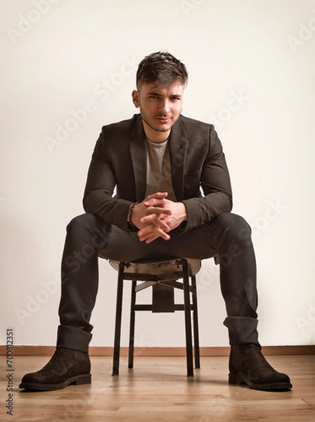 Obraz Photo of a businessman seated on a chair wearing a suit