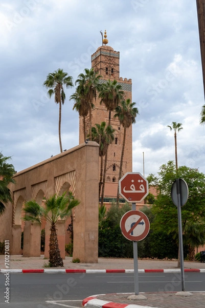 Obraz Photo of the tower of the Koutoubia Mosque. In the photo there is a stop sign written in Arabic. Cloudy day.