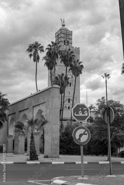 Obraz Photo of the tower of the Koutoubia Mosque. In the photo there is a stop sign written in Arabic. Cloudy day.
