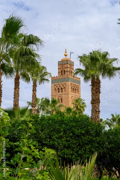 Obraz Photo of the upper part of the tower of the Koutoubia mosque in the city of Marrakech, tower covered by trees and palm trees. Cloudy day.