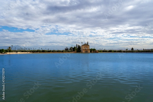 Obraz Photo of the Menara Gardens in the city of Marrakech. Photo of the lake with the house at the end of the lake. The house reflected in the lake. Cloudy day.