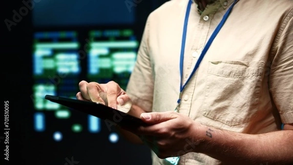 Obraz Meticulous technician doing checkup, inputing data on tablet of needed fixes in server hub housing advanced data storage infrastructure supporting critical IT workloads, close up