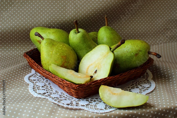 Fototapeta Green pears in a basket and one of them cut into the share.