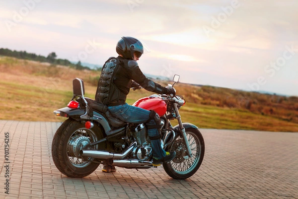 Fototapeta Biker man wearing a leather jacket and sunglasses sitting on his motorcycle