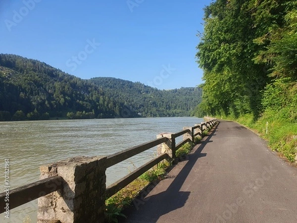 Fototapeta Beautiful bike path at famous Danube River: Donauradweg next to the river on a sunny day with clear blue sky and copy space for text, austria