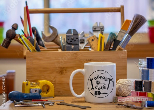 Obraz Repair Cafe logo mug with repair tools on table in cafe used as a repair centre consumer activism to repair household items to reduce waste and support a sustainable lifestyle