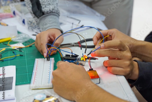 Fototapeta Students experiment with simple electronic circuits. Principles of traffic light circuits. Soft and selective focus.