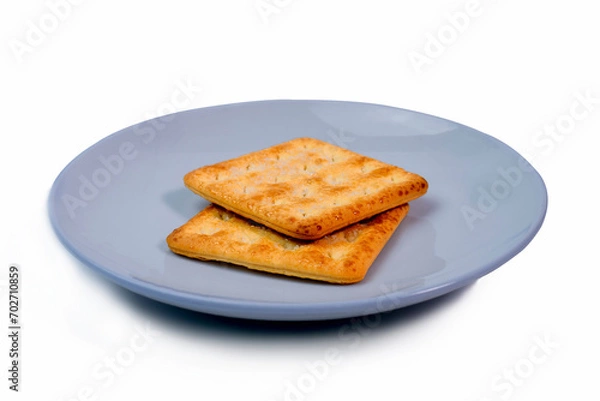Obraz Two crackers placed on a small white ceramic plate. White background. Biscuits