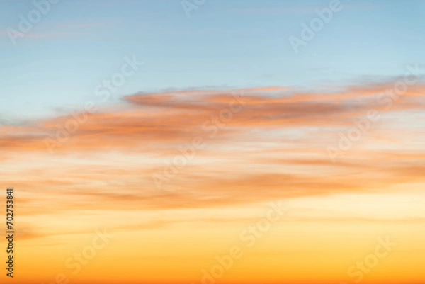 Fototapeta The dramatic colors of the sunset in the sky gradient from blue to orange.