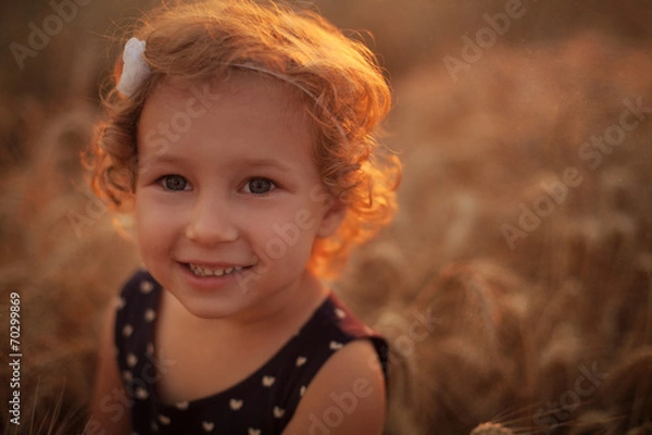 Fototapeta Smiling happy little girl on the wheat field