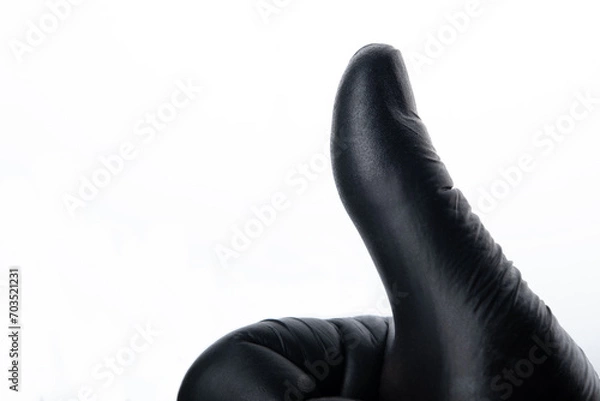 Fototapeta Thumbs up using black glove isolated on white background. Positive concept.