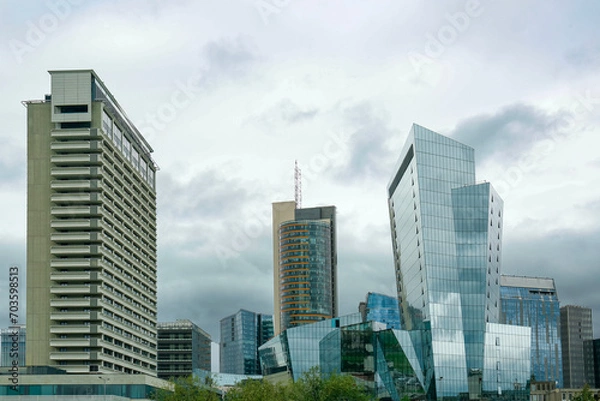 Fototapeta View of modern skyscrapers in city on cloudy day