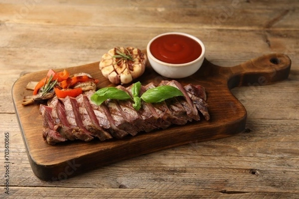 Fototapeta Delicious grilled beef steak with spices and tomato sauce on wooden table