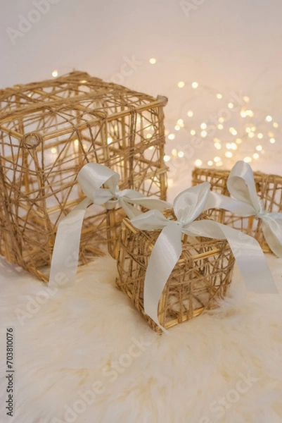Fototapeta Wicker gift box with a white bow on a white fur background