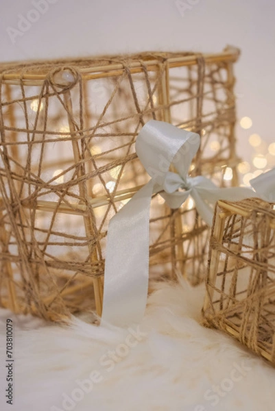 Fototapeta Wicker gift box with a white bow on a white fur background