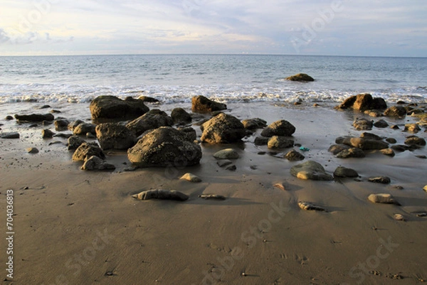 Fototapeta Black rocks on sandy beach