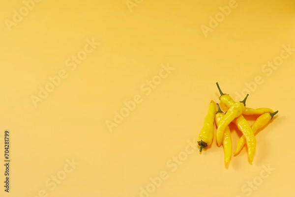 Obraz 黄色系唐辛子を複数右下に複数配置した黄色系背景あり俯瞰撮影