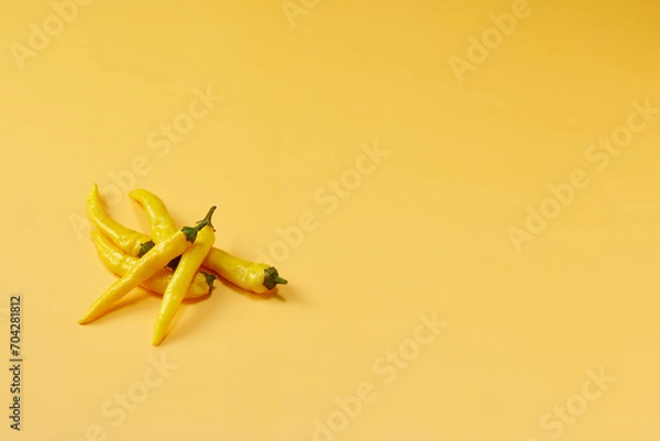 Obraz 黄色系唐辛子を複数左下に複数配置した黄色系背景あり俯瞰撮影