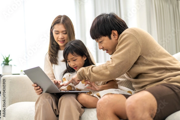 Obraz Father and mother with asian kid girl learn on laptop computer reviewing lesson study with online education e-learning.student look for educational knowledge in homeschool at home.Education