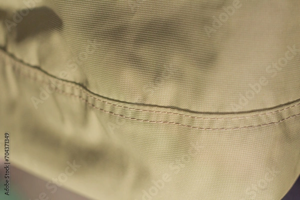 Fototapeta protective work clothes in beige and brown colors. Factory stitches on thick fabric. Close-up texture