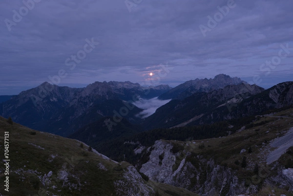 Obraz Moon just before setting down shines a radiant glow on the fog in the valley. A view from the Mangart saddle towards the setting full moon. Mangart (2679 m) is a mountain in the Julian Alps.