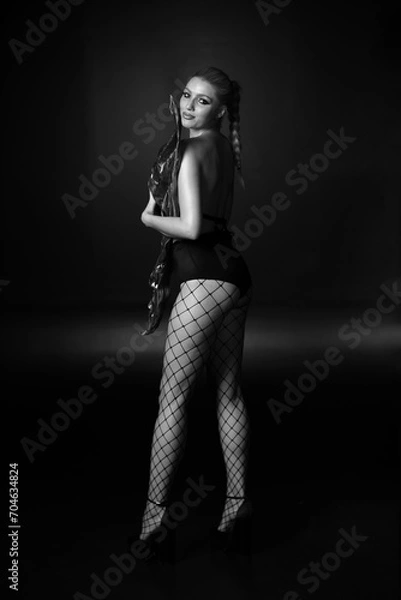 Fototapeta Low key portrait of woman in stockings in a grid in black and white