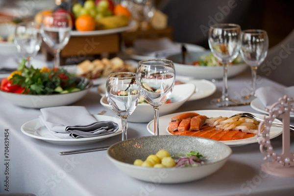 Fototapeta glasses and plates with snacks on the festive table in the restaurant