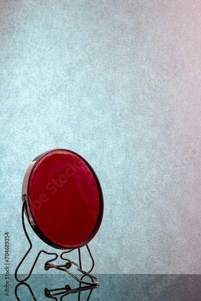 Obraz ound mirror on a dark table with a blue wall
