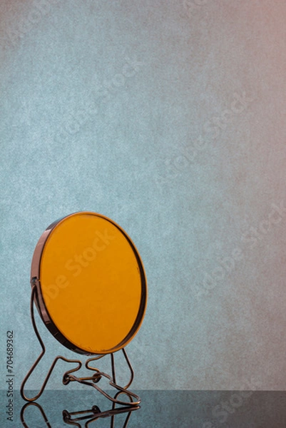 Obraz Round mirror on a dark table with a blue wall in the background