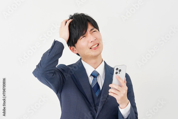 Fototapeta スマートフォンを持って頭を抱えるビジネスマン　白背景