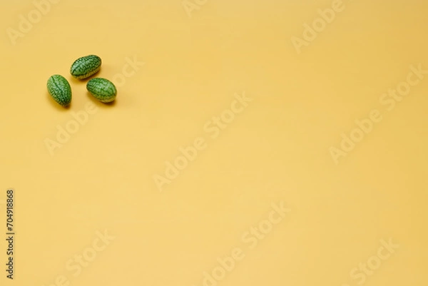 Obraz マイクロきゅうりを数粒左上に配置した黄色系背景あり俯瞰撮影