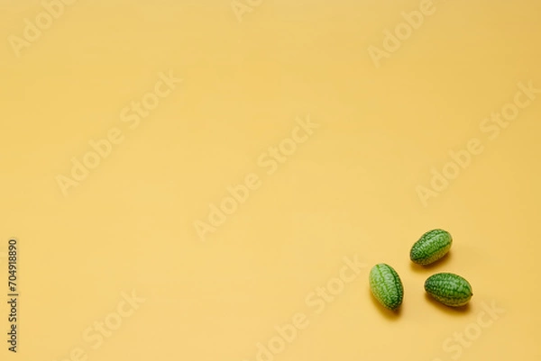 Obraz マイクロきゅうりを数粒右下に配置した黄色系背景あり俯瞰撮影