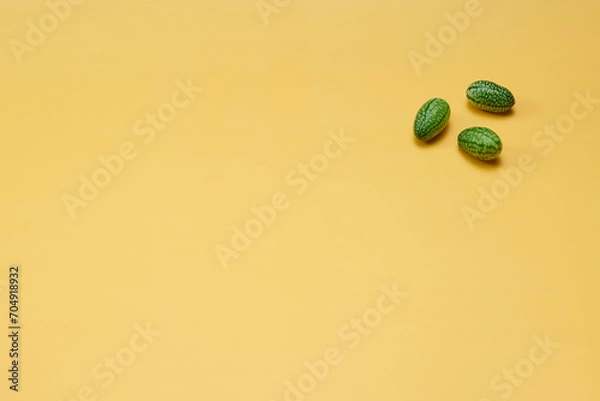 Obraz マイクロきゅうりを数粒右上に配置した黄色系背景あり俯瞰撮影