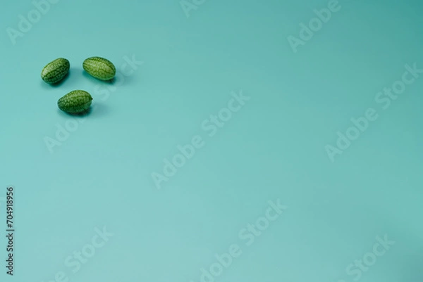 Obraz マイクロきゅうりを数粒左上に配置した緑色系背景あり俯瞰撮影