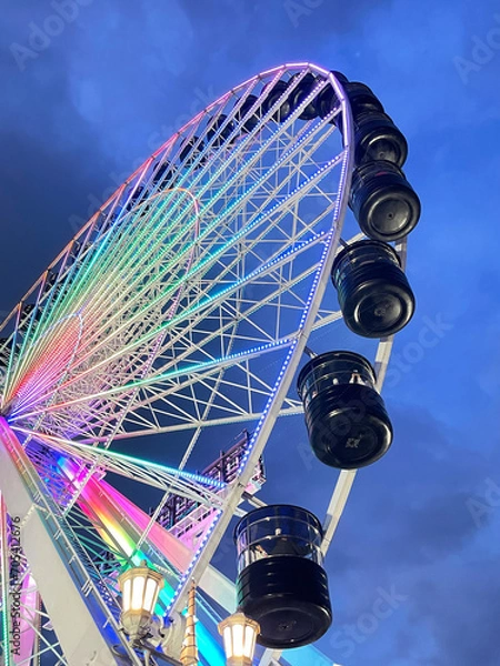 Fototapeta looking up at a colorful ferris wheel at night