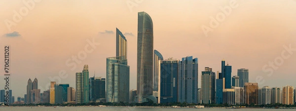Fototapeta The corniche and skyline of Abu Dhabi after sunset, with futuristic and modern skyscrapers. Blue hour, pink sky.