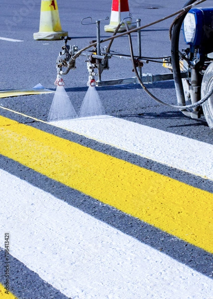 Obraz a team of workers drawing a pedestrian crossing in early spring using automated equipment on fresh asphalt