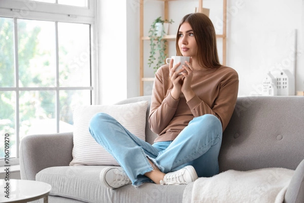 Fototapeta Young woman with cup of hot tea at home