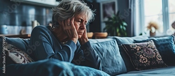 Fototapeta Senior Woman Sitting On Sofa At Home Suffering From Depression. with copy space image. Place for adding text or design