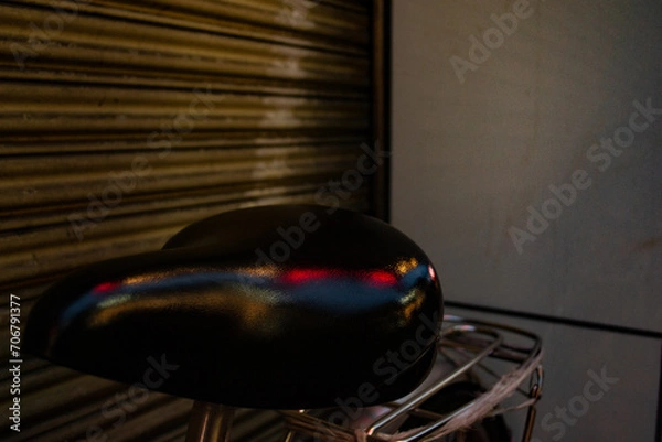 Fototapeta Red and blue lights reflecting off of a bicycle seat.