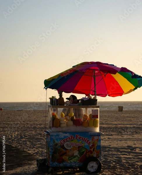 Fototapeta Fruit Cart with colorful umbrella by the beach at sunset in Santa Monica, Los Angeles.