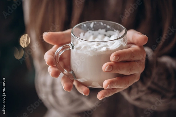 Fototapeta Transparent glass mug of cocoa with marshmallows in female hands. Close-up. New Year's portrait.