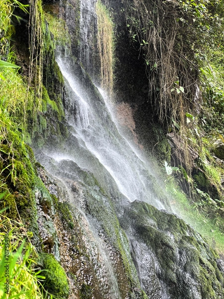Fototapeta Waterfall splashing against the cliffs as it comes down the mountain background