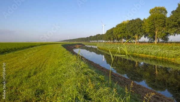 Obraz Canal through a hazy landscape at sunrise