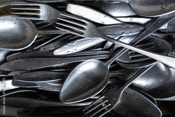Fototapeta Pile of old worn vintage cutlery. Background of aluminium forks and spoons. Top view