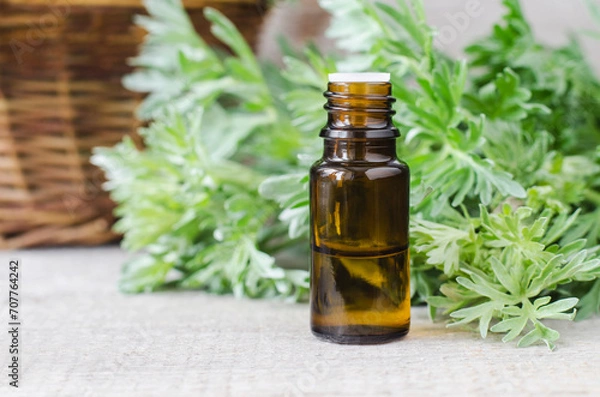 Obraz Small bottle with essential wormwood oil (extract, tincture, infusion). Old wooden background. Aromatherapy, spa and herbal medicine concept.